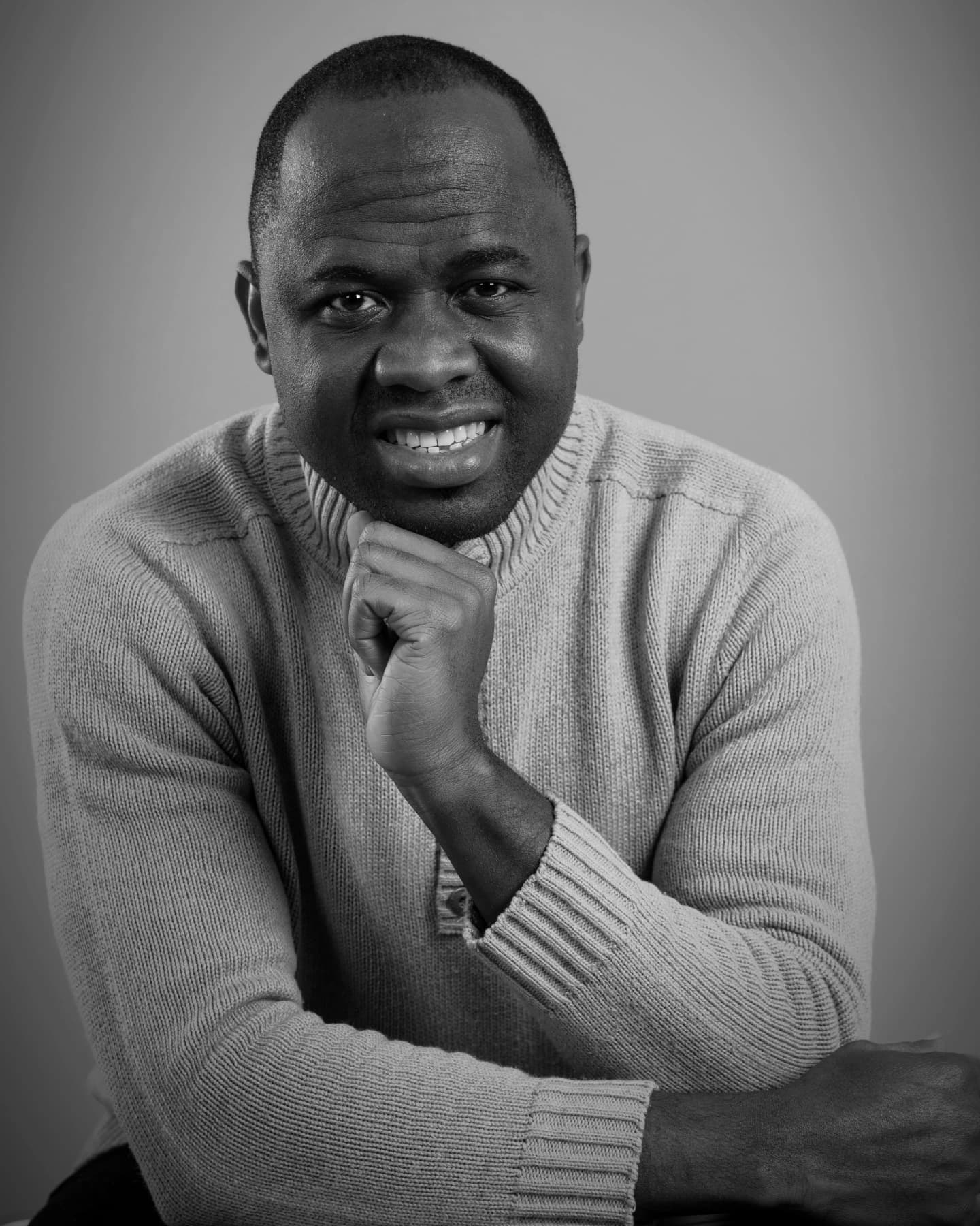 Black and white portrait of the photographer behind Precious Diamond, smiling with one hand at the chin